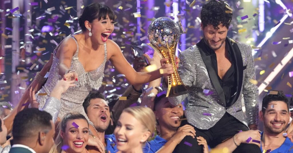 Xochitl Gomez and Val Chmerkovskiy celebrating their victory with the Mirrorball Trophy on the Dancing With The Stars stage.